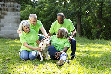 A group of charity volunteers in green shirts seated on the grass, with a dog lying beside them.